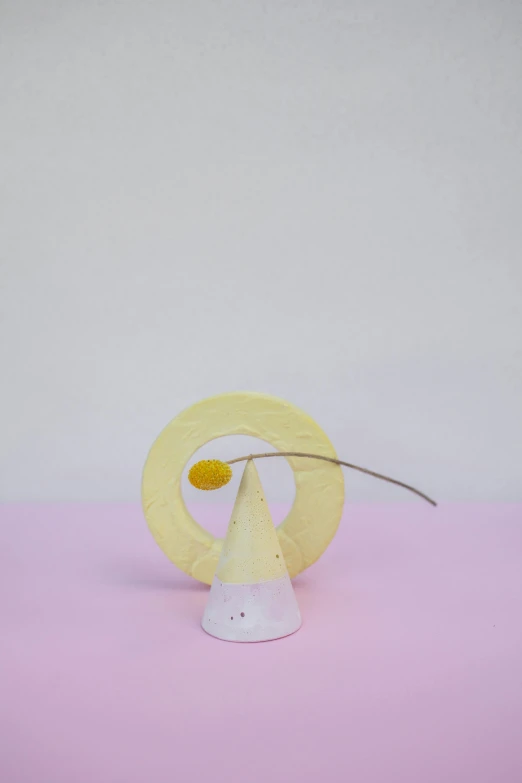 a paper cone sitting on top of a pink surface, an abstract sculpture, inspired by jeonseok lee, yellow mist, singularity sculpted �ー etsy, ikebana, portrait of small