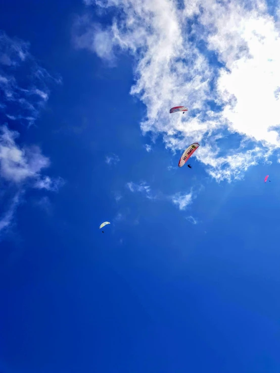 a group of people flying kites in a blue sky, slide show, gopro photo