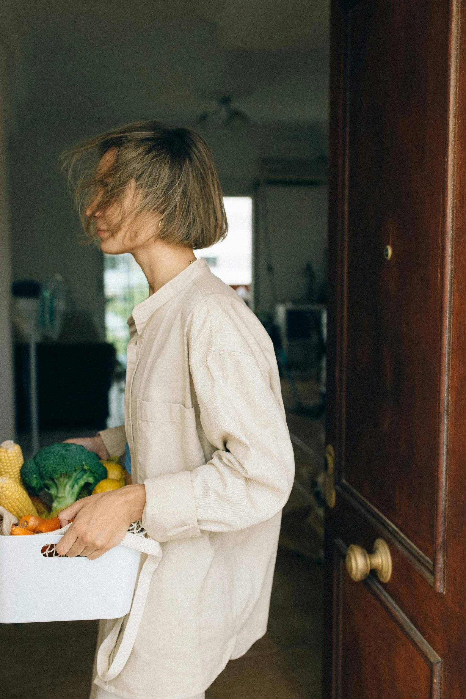 a woman carrying a box of fruit and vegetables, pexels contest winner, happening, wearing a linen shirt, opening door, profile image, home