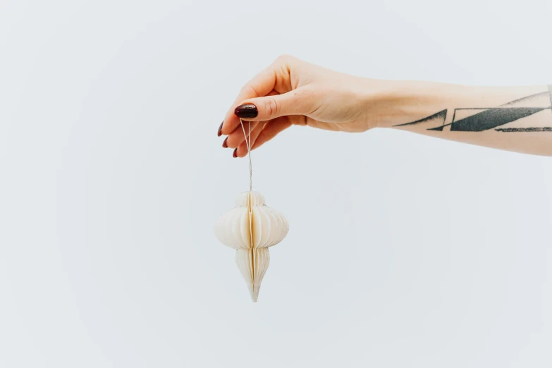 a person holding a piece of paper in their hand, a marble sculpture, unsplash, purism, puka shell necklace, white background and fill, holiday season, nautical siren