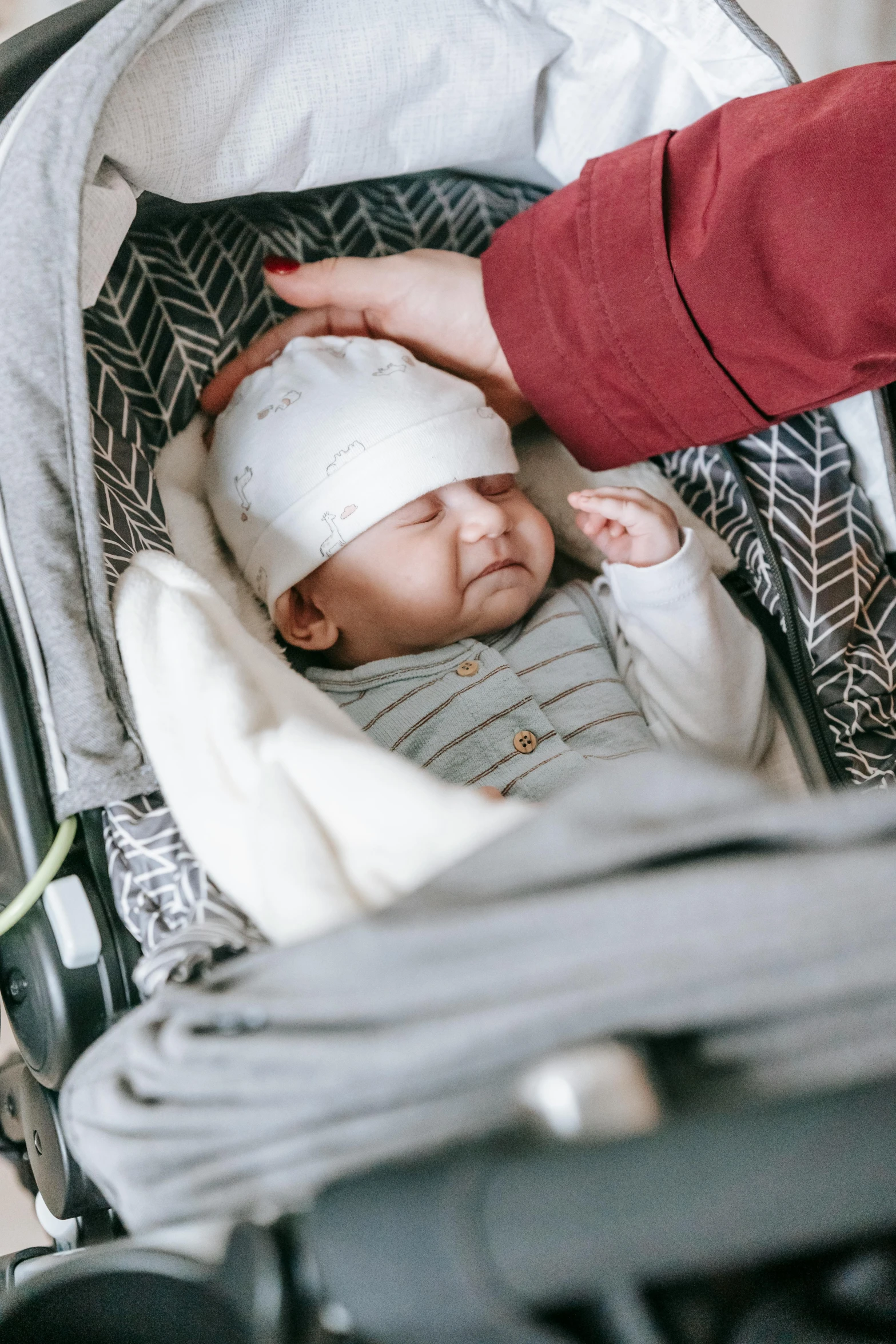 a person putting a bandage on a baby in a stroller, by Carey Morris, pexels, wearing a grey wizard hat, nearly napping, promo image, patterned