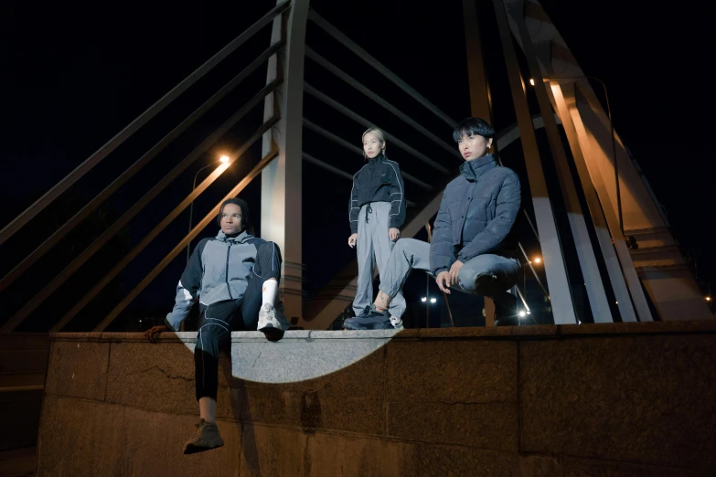 a group of young men sitting on top of a bridge, inspired by Zhang Xiaogang, unsplash, lyco art, wearing a turtleneck and jacket, moonlight grey, 3 - piece, reflective material