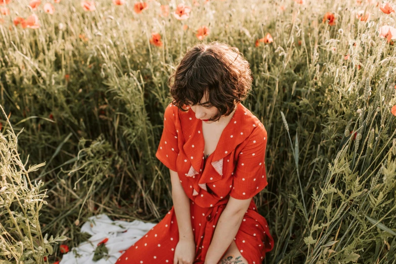 a woman sitting in a field of red flowers, by Emma Andijewska, pexels contest winner, wearing an orange jumpsuit, polka dot, avatar image, woman in dress