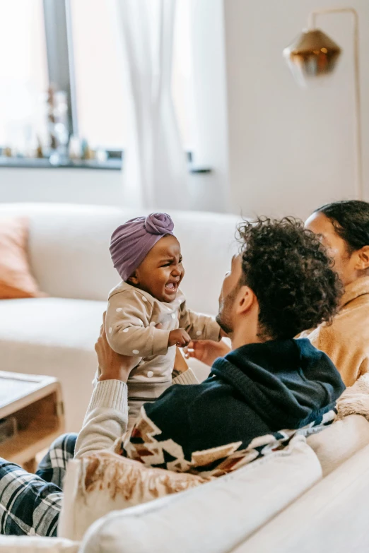 a man sitting on a couch holding a baby, pexels contest winner, mix of ethnicities and genders, excited, on a coffee table, 3 - piece