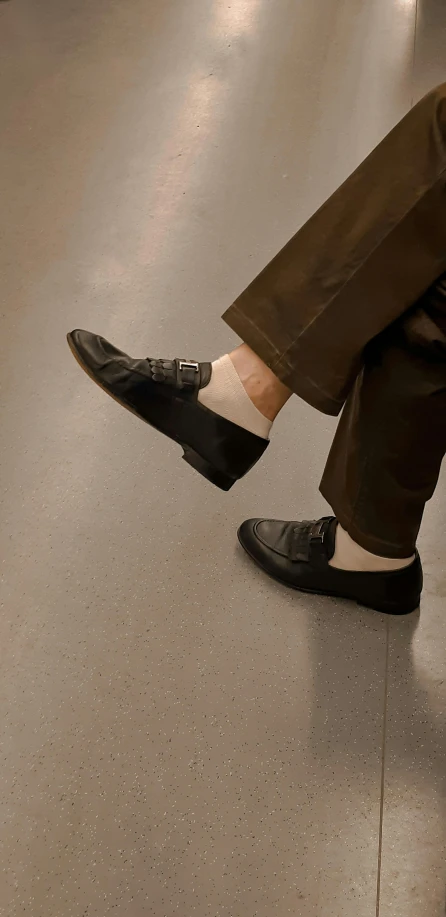 a close up of a person sitting on a bench, grey pants and black dress shoes, he is dancing, wearing kneesocks, taken in the early 2020s