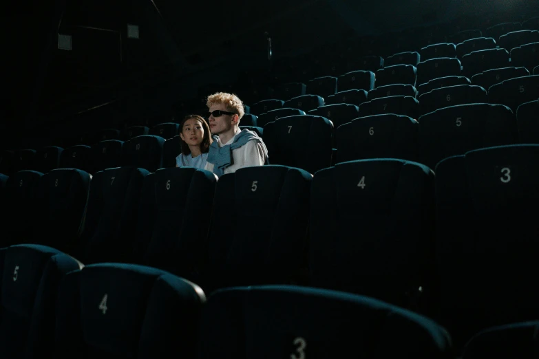 a couple of people sitting next to each other in a theater, by Adam Marczyński, pexels contest winner, realism, sci-fi movie still, summer season, instagram picture, light cinematic