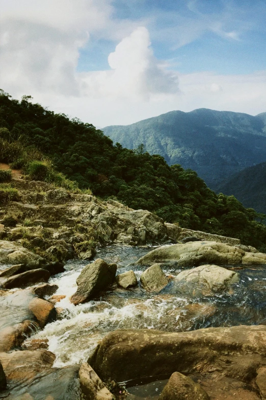 a river running through a lush green hillside, an album cover, inspired by Samuel Silva, trending on unsplash, hurufiyya, sri lankan landscape, sitting on rocks, panoramic view, 2 5 6 x 2 5 6 pixels