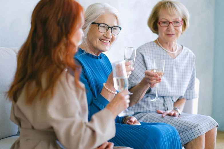 three women sitting on a couch holding wine glasses, by Hazel Armour, pexels, older woman, on a white table, sparkling, an elderly