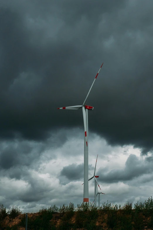 a group of wind turbines under a cloudy sky, by Adam Marczyński, pexels contest winner, dark storm clouds, upset, grey, museum quality photo