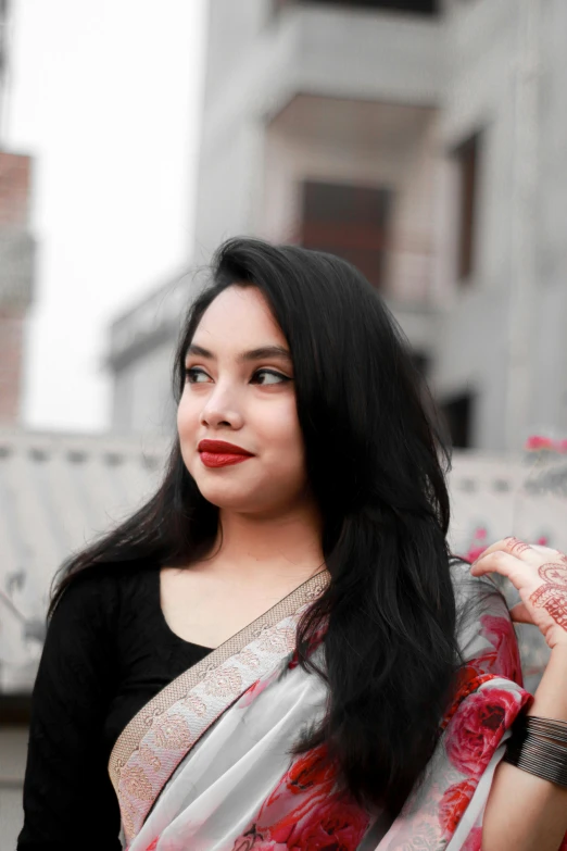 a woman wearing a sari standing in front of a building, an album cover, pexels contest winner, vibrent red lipstick, headshot profile picture, assamese aesthetic, black in
