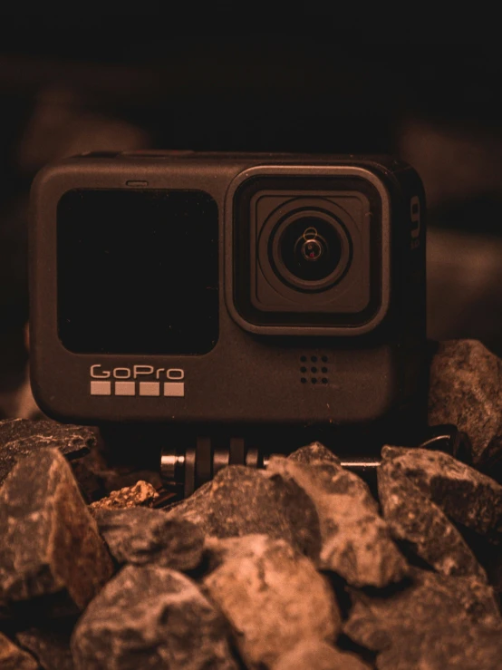 a gopro camera sitting on top of a pile of rocks, inspired by Elsa Bleda, unsplash, profile image, home video footage, indoor shot, black 3 d cuboid device