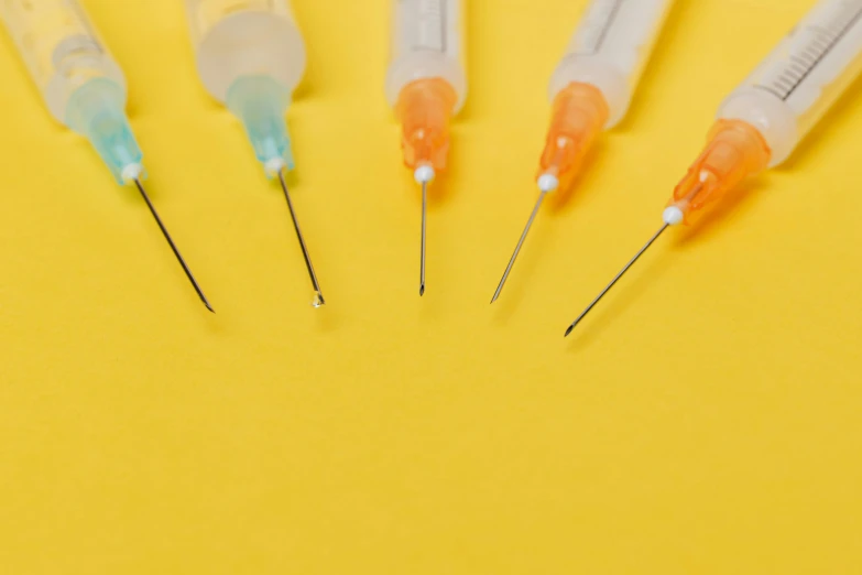 a group of injections sitting on top of a yellow surface, trending on pexels, small quills along it's back, vibrant threads, iv pole, rounded lines