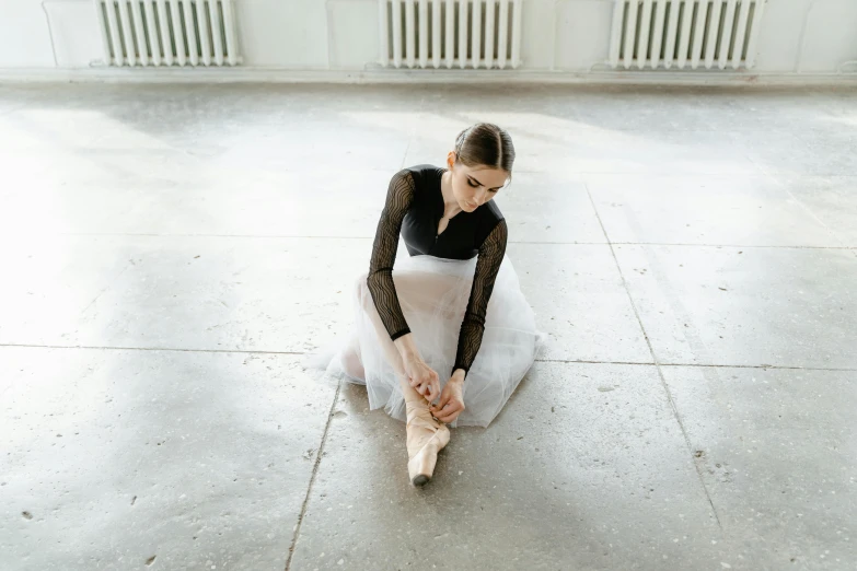 a woman sitting on the ground tying up her ballet shoes, by Elizabeth Polunin, pexels contest winner, arabesque, sitting in an empty white room, gif, valeriy vegera, an elegant