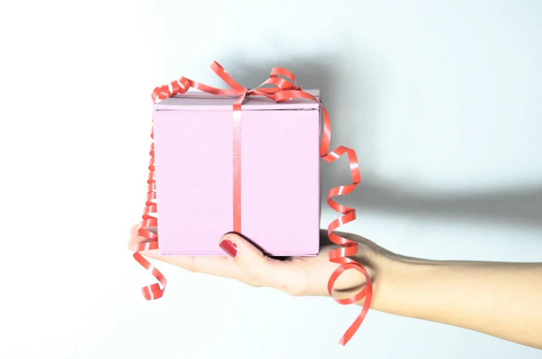 a person holding a pink box with a red ribbon, pexels contest winner, background image, minimalistic, decoration, coloured