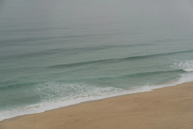 a man riding a surfboard on top of a sandy beach, by Romain brook, pexels contest winner, nazare (portugal), photo of the middle of the ocean, very sparse detail, no people 4k