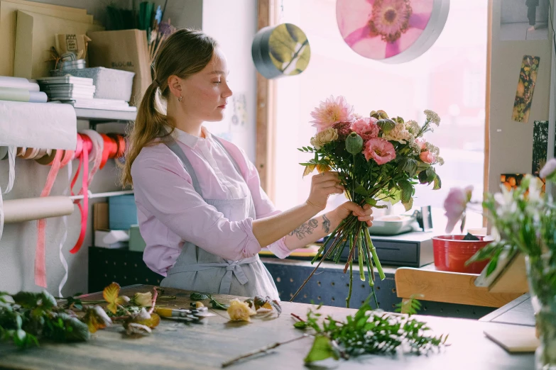 a woman arranging flowers in a flower shop, pexels contest winner, process art, on kitchen table, looking off to the side, high delicate details, artist wearing overalls