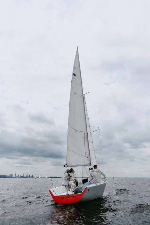 a sailboat in the middle of a body of water, on a cloudy day, action shot, skyline showing, espoo