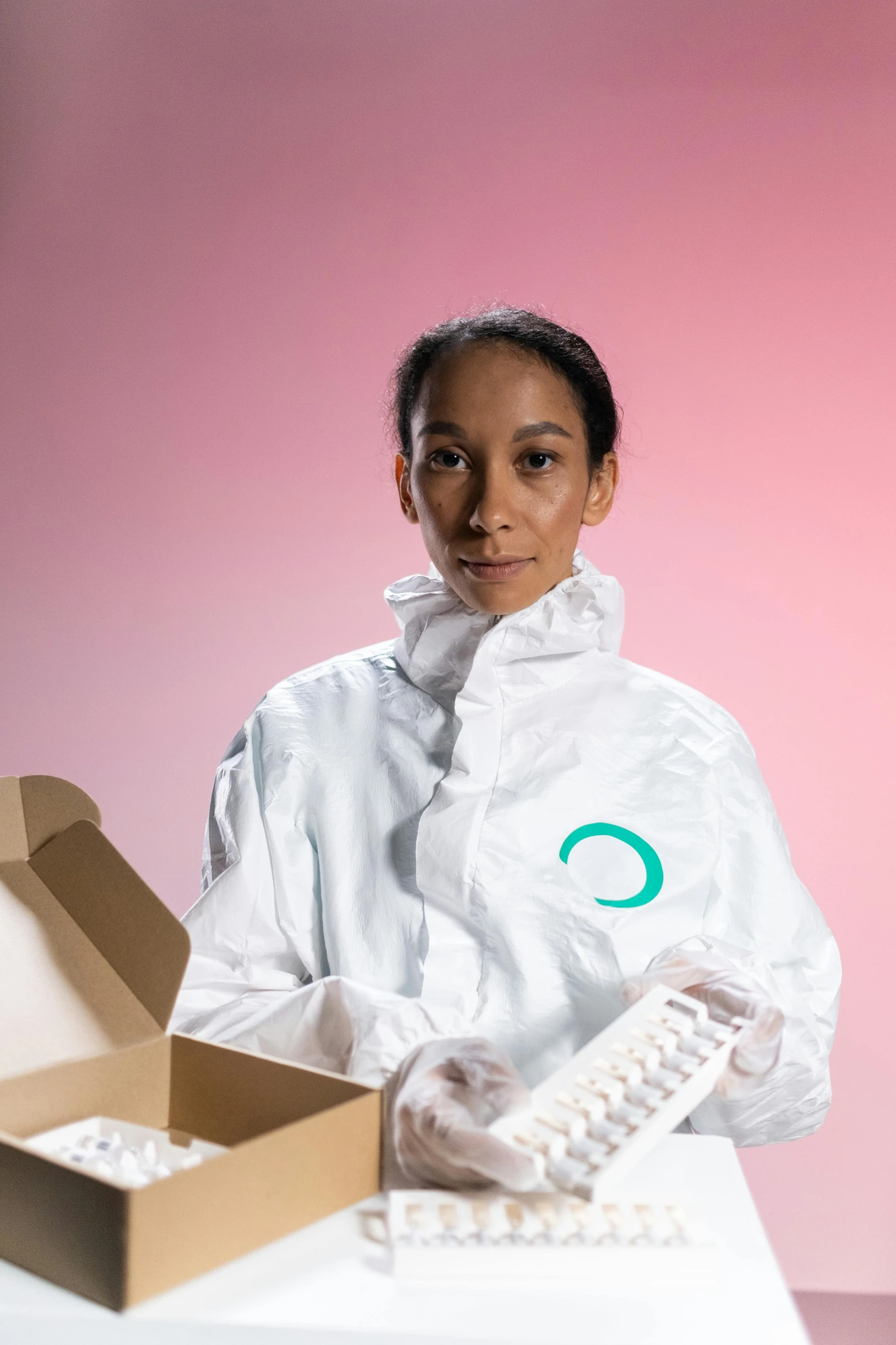 a woman in a white lab coat holding a box, by Olivia Peguero, antipodeans, white and teal garment, cryogenic pods, healthcare worker, future inflatable jacket