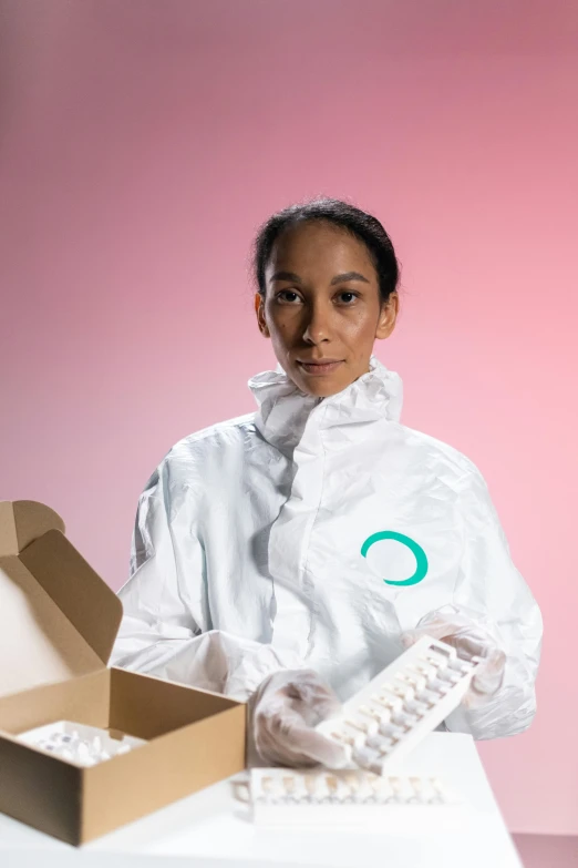 a woman in a white lab coat holding a box, by Olivia Peguero, antipodeans, white and teal garment, cryogenic pods, healthcare worker, future inflatable jacket