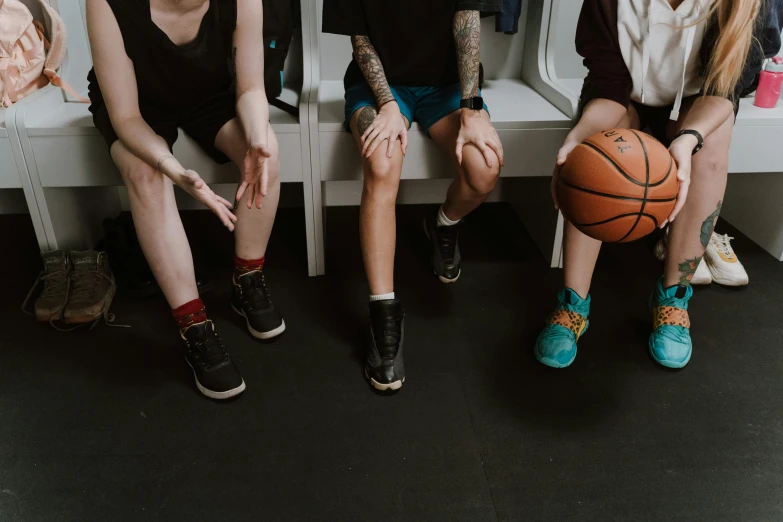 a group of people sitting next to each other on a bench, trending on pexels, basketball ball, wearing kneesocks, local gym, holding court