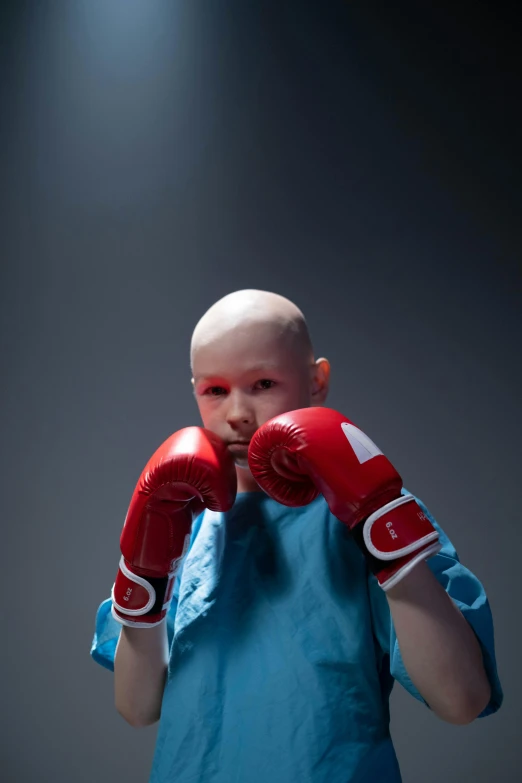 a man in a blue shirt and red boxing gloves, an album cover, by artist, shutterstock contest winner, bald head, children's, tumors, photo of the girl