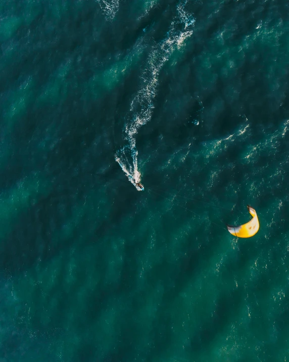 a couple of people riding surfboards on top of a body of water, parachutes, bird's view, unsplash photography, thumbnail