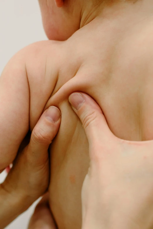 a close up of a person holding a baby, showing her shoulder from back, muscle tissue, manipulation, points