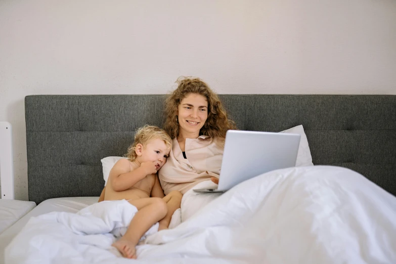 a woman and child on a bed with a laptop, by Carey Morris, pexels, happening, avatar image, white, bedhead, casually dressed