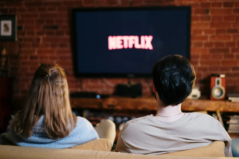 two people sitting on a couch watching tv, pexels, serial art, netflix logo, large screen, playing games, cast