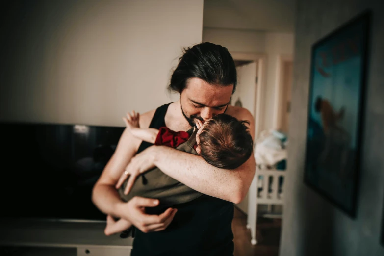 a woman holding a baby in her arms, by Sebastian Spreng, pexels contest winner, bearded, avatar image, daddy/fatherly, at home