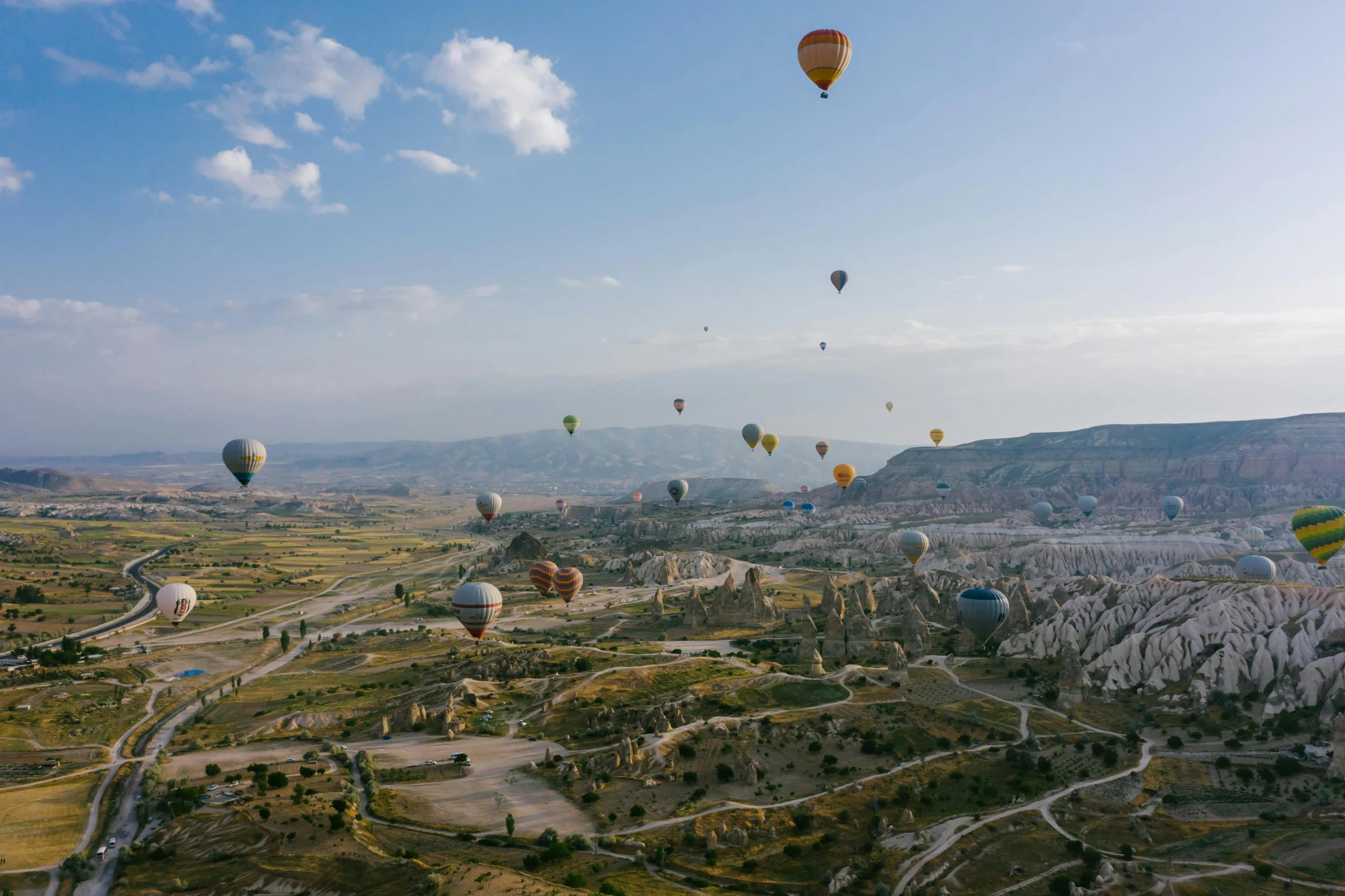 a group of hot air balloons flying over a valley, pexels contest winner, ancient marble city, unsplash 4k, bird\'s eye view, 2 0 2 2 photo