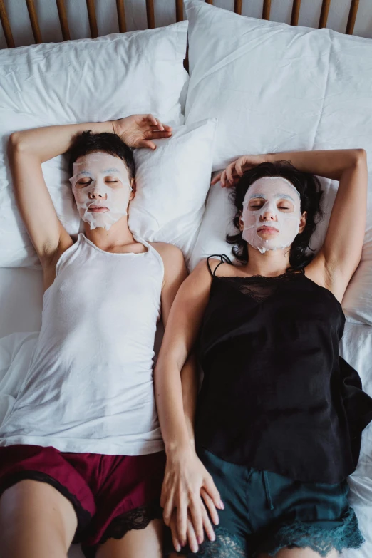 a couple of women laying on top of a bed, one single mask, perfect facial symettry, roomies, hypercomplex