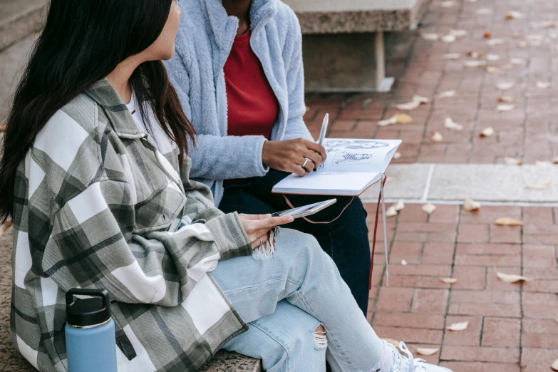 two women sitting next to each other on a bench, trending on pexels, academic art, writing on a clipboard, woman in streetwear, background image, on a notebook page