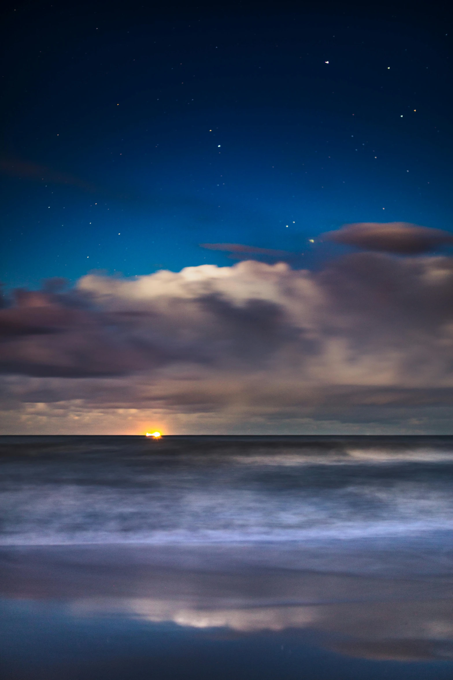 a large body of water under a cloudy sky, by Jesper Knudsen, moonlit ocean, sunset at the beach, stars, award - winning photo ”