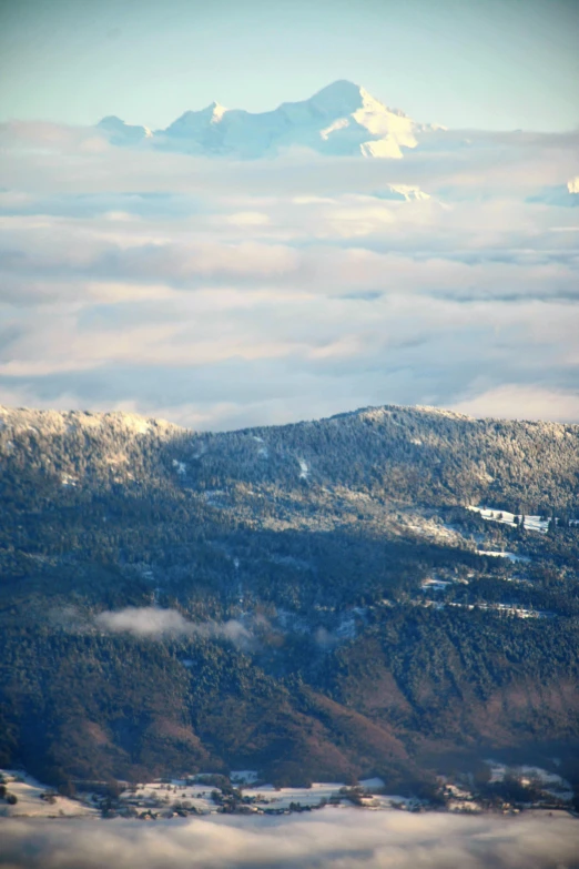 a plane flying over a mountain covered in snow, forest in the distance, altostratus clouds, slide show, coast