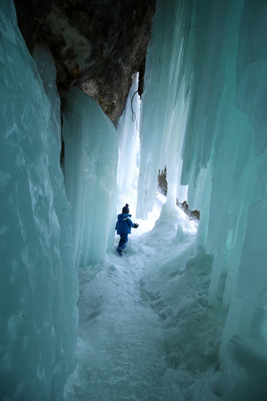 a person standing in the middle of an ice cave, by Erwin Bowien, girl walking in a canyon, wyoming, fujifilm”