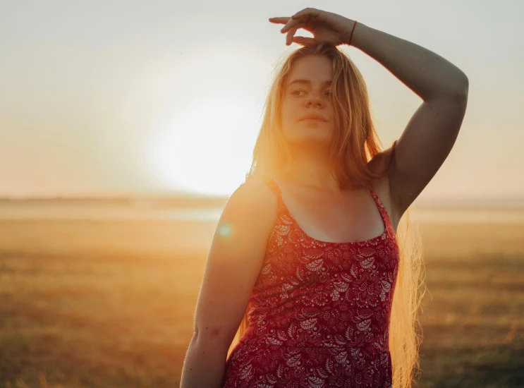 a woman standing in a field at sunset, pexels contest winner, alluring plus sized model, wearing red tank top, teenage girl, sunbathed skin