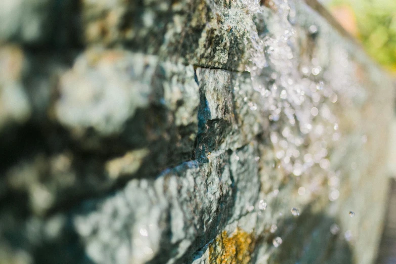 a close up of a stone wall with water coming out of it, a macro photograph, unsplash, sparkling in the sunlight, background image, ((rocks))