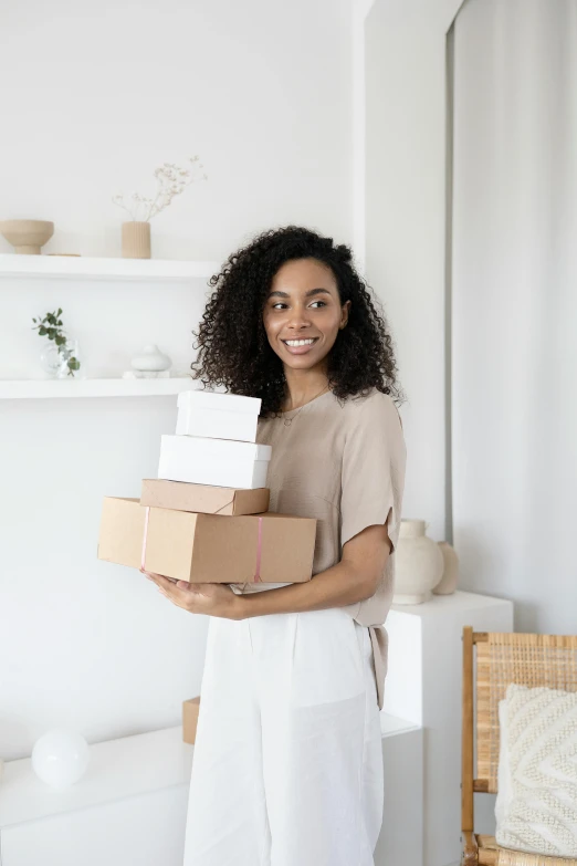 a woman holding a stack of boxes in a living room, by Eden Box, pexels contest winner, renaissance, white background, with afro, brown and white color scheme, postage