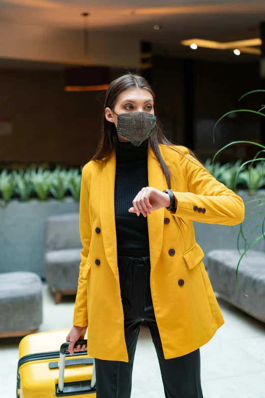 a woman in a yellow coat with a yellow suitcase, trending on pexels, balaclava mask, wearing a watch, standing in a restaurant, wearing a blazer