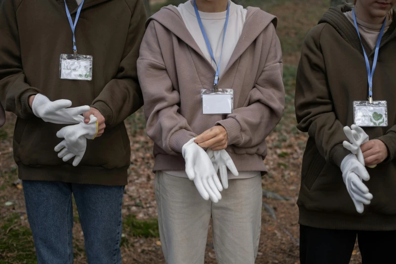 a group of people standing next to each other, a colorized photo, inspired by Vanessa Beecroft, unsplash, white long gloves, woodlands, partially cupping her hands, environmental