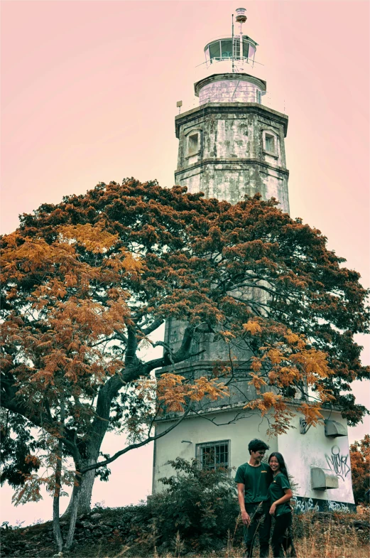 a man and a woman standing in front of a lighthouse, a colorized photo, by Miroslava Sviridova, baroque, a beautiful tree, manila, in fall, church