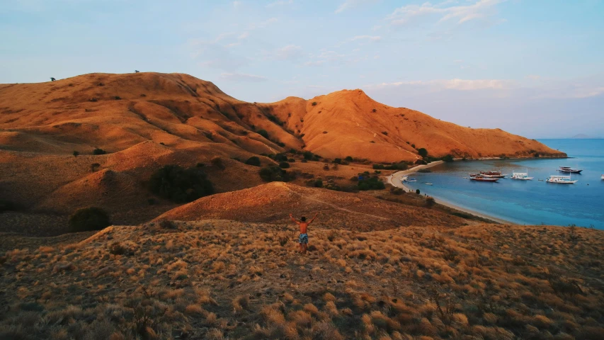 a group of boats floating on top of a body of water, by Daniel Lieske, pexels contest winner, sumatraism, girl walking between dunes, grassy hills, sunset panorama, photo on iphone