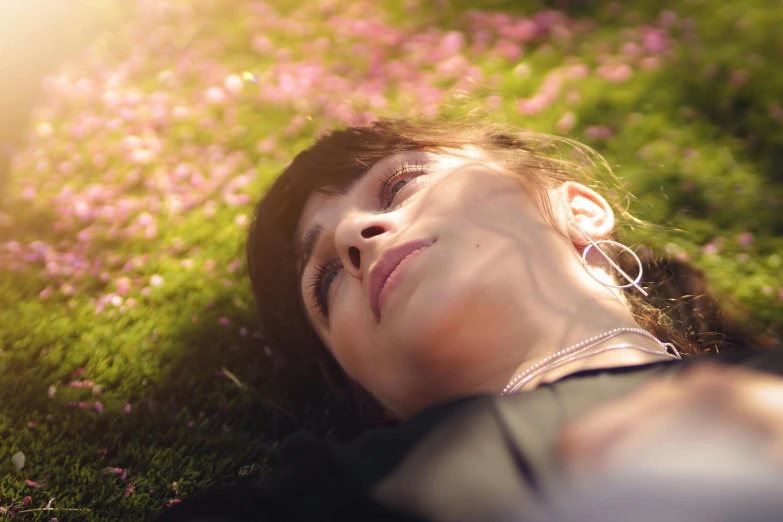 a woman laying on top of a lush green field, pexels contest winner, realism, soft light 4 k in pink, anamorphic bokeh and lens flares, avatar image, close-up portrait film still