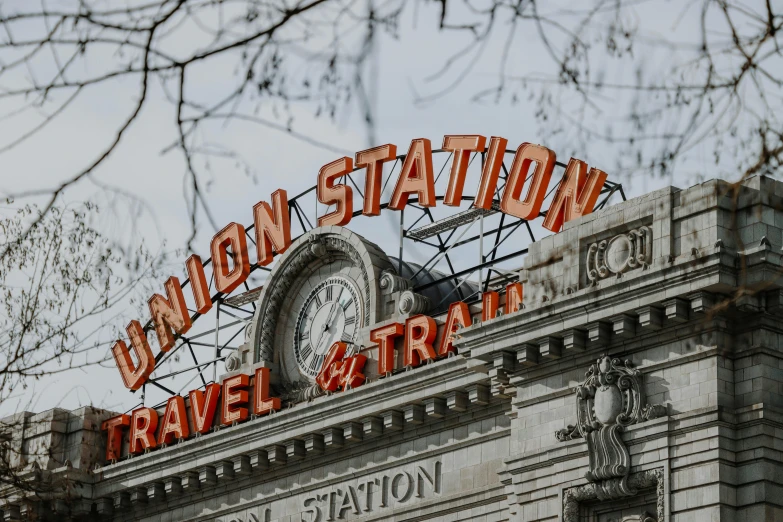 a close up of a clock on top of a building, a cartoon, inspired by Ian Hamilton Finlay, unsplash contest winner, art nouveau, train station, bright signage, statues, conde nast traveler photo