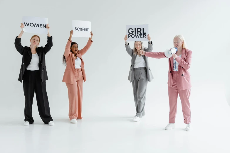 a group of women holding signs that say girls power, trending on pexels, full body with costume, on grey background, wearing a suits, human design