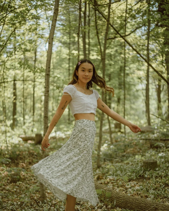 a woman standing on a log in the woods, unsplash, renaissance, wearing crop top, dressed in long fluent skirt, 35 mm photo, isabela moner