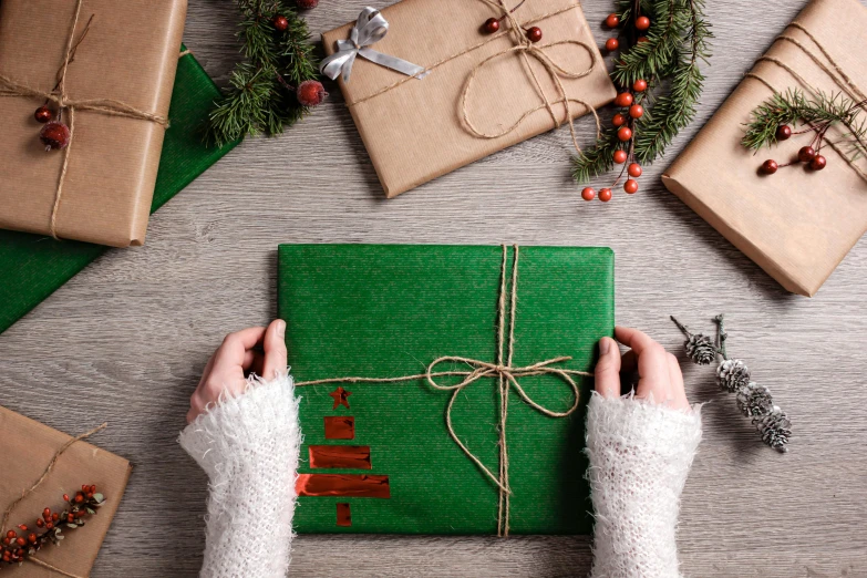 a person wrapping christmas presents on a table, an album cover, by Eden Box, pexels contest winner, green and brown tones, avatar image, closeup - view, small