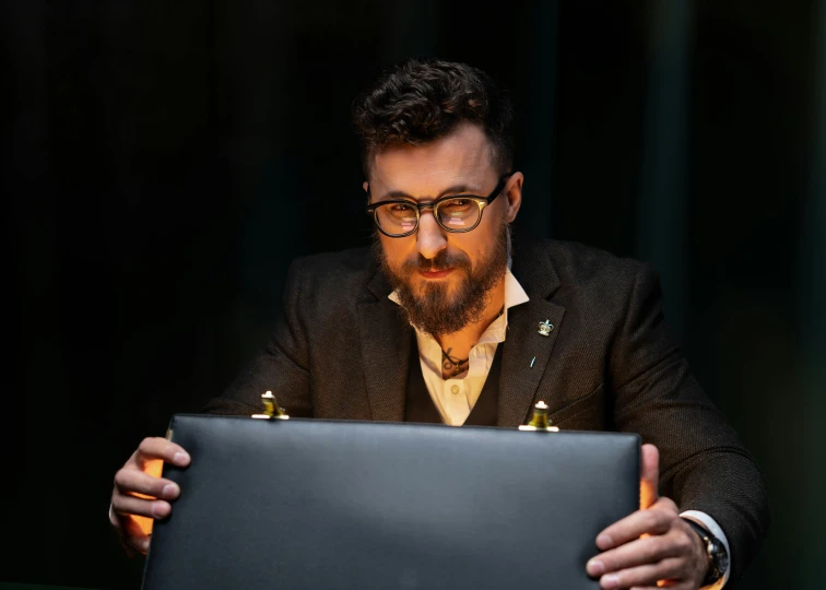 a man sitting in front of a laptop computer, by Daniel Gelon, production photo, with glasses and goatee, lachlan bailey, performing