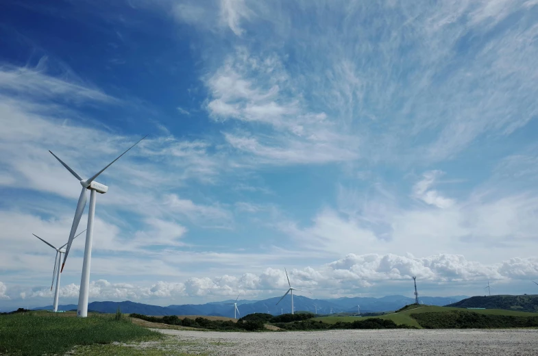 a group of wind turbines sitting on top of a lush green hillside, unsplash contest winner, panorama view of the sky, taken on an iphone, **cinematic, whealan